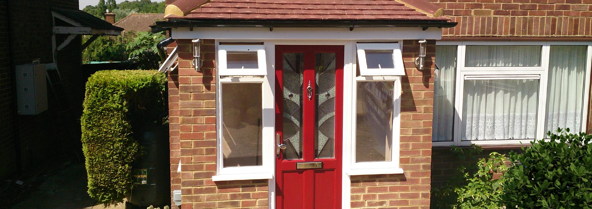 Brick porch installation with red door and casement windows